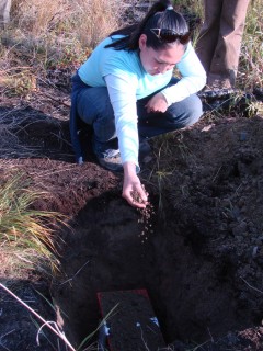 Cathy dropping earth into the hole for the Alaska Earth Treasure Vase. This vase was buried far out in the tundra, never to be disturbed